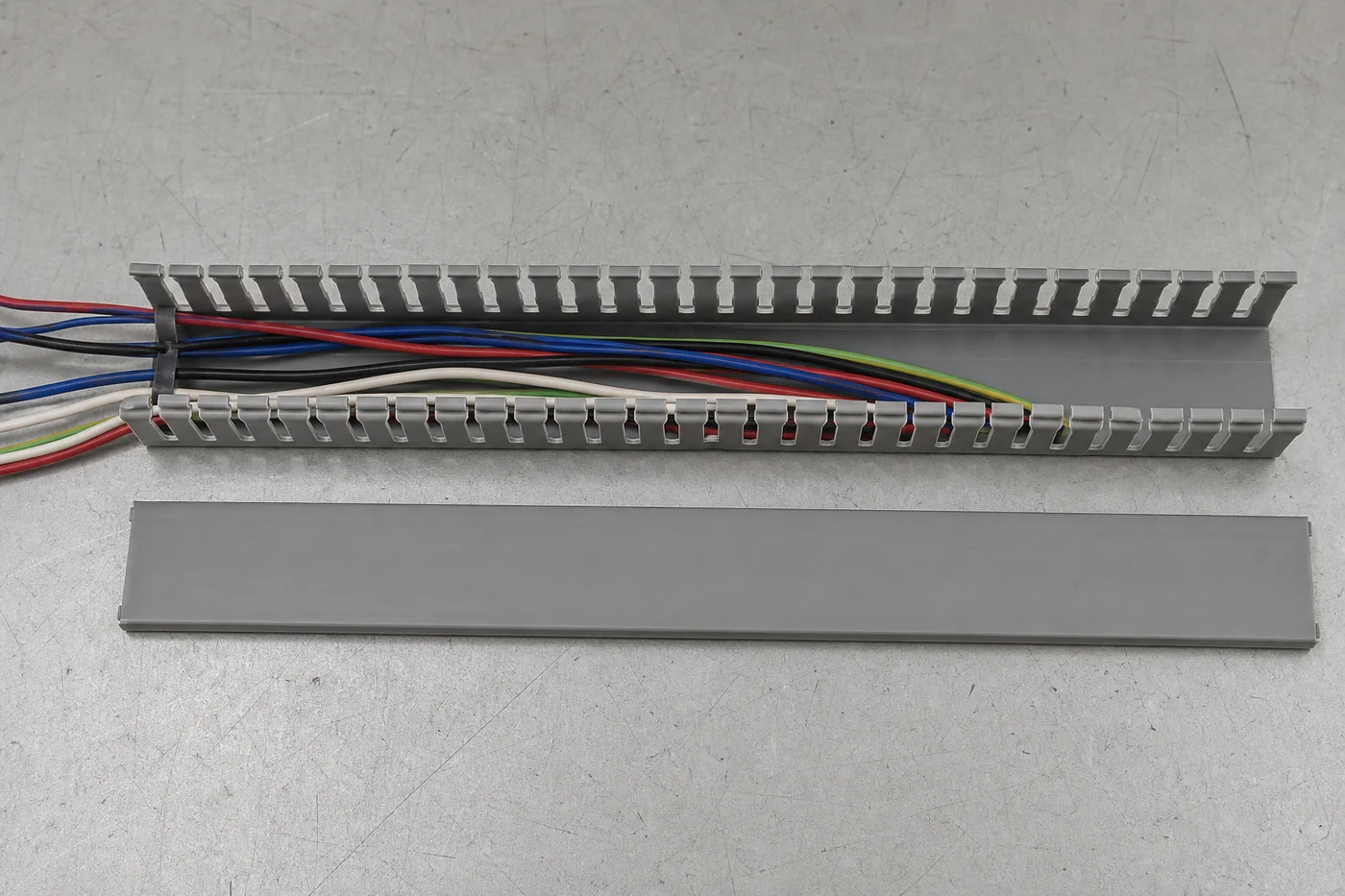 Open gray slotted wiring duct with an orderly wire bundle and spare internal capacity